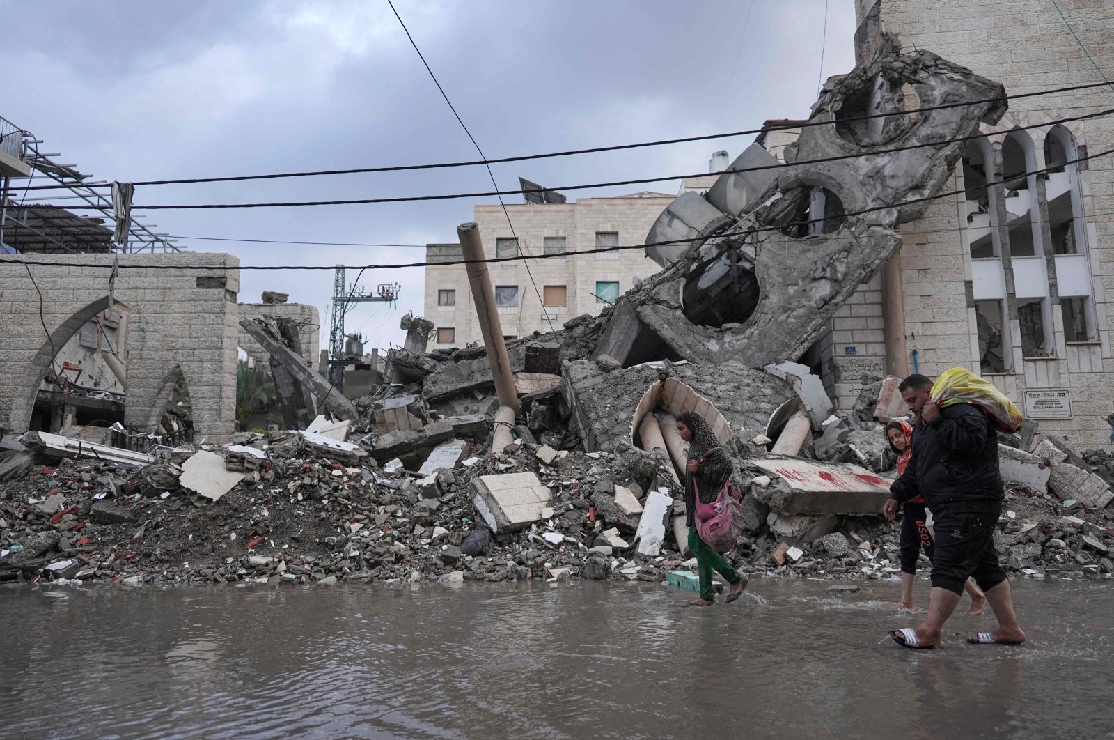 Palestinians wade in rainwater as they walk past a destroyed mosque on the first day of the Eid al-Fitr festival marking the end of the holy month of Ramadan, Deir el-Balah, Gaza Strip, Palestine, April 10, 2024. (AFP Photo)